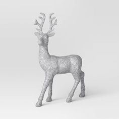 a silver glitter deer standing on top of a white floor next to a gray wall