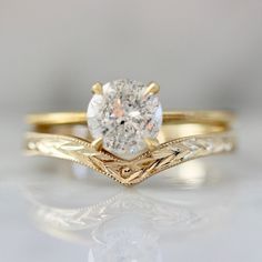 a yellow gold engagement ring with an oval cut diamond in the center and leaves on the band