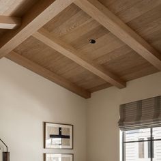 a bed sitting under a wooden ceiling next to a window