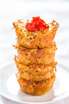 baked parmesan hash brown cups stacked on top of each other with tomatoes in the middle