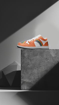 an orange and white shoe sitting on top of a cement block