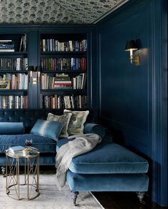 a living room with blue couches and bookshelves