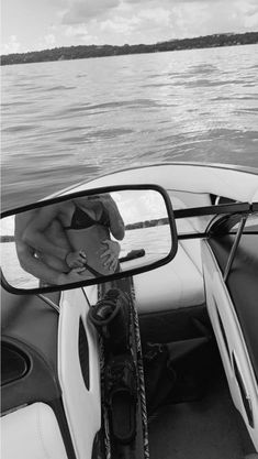 a man sitting on the back of a boat in front of a rear view mirror