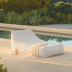 a white bean bag chair sitting next to a pool with a blanket draped over it