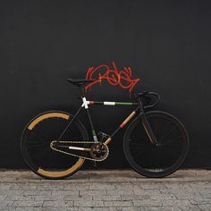 a bike parked next to a black wall with graffiti on it's side and the seatposts