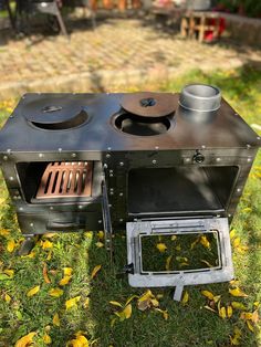 an outdoor stove sitting in the middle of some grass