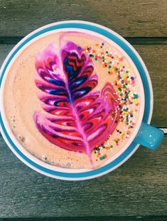 a cup of coffee with a painted leaf on it and sprinkles in the foam