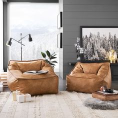 a living room with two brown chairs and a table in front of a large window