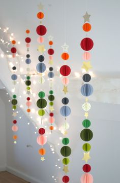 a room filled with lots of colorful paper balls hanging from the ceiling and lights on the wall