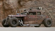 an old rusted out toy truck sitting on top of a wooden table next to a rock wall