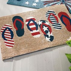 the door mat is decorated with flip flops and stars on it, along with a potted plant