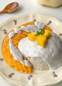 a white plate topped with rice covered in mango slices and sauce next to a wooden spoon