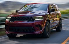 a red dodge suv driving down the road