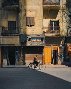 a man riding a bike down a street next to tall buildings with balconies