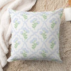 a white and blue pillow sitting on top of a fluffy rug next to a blanket