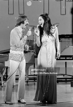 two people standing next to each other in front of a keyboard and microphone on stage