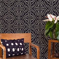 two wooden chairs sitting next to each other in front of a black and white wall