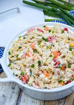 a white bowl filled with pasta salad on top of a wooden table