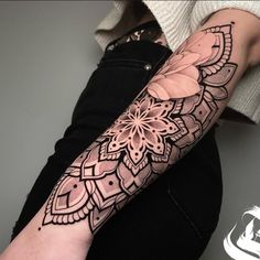 a woman's arm with an intricate tattoo design on the left forearm and wrist