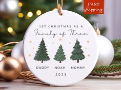 a ceramic ornament with three christmas trees on it and the words, first christmas as family of three