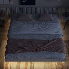 a bed with two pillows on top of it in a room that has wood flooring