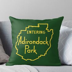 a green and yellow throw pillow with the words, entering adirondack park