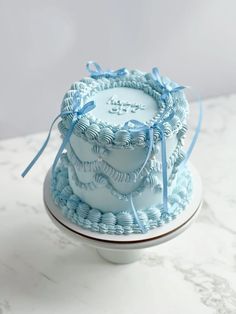 there is a blue cake on top of a white plate with ribbon around the edges