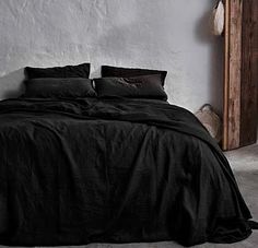 a bed with black sheets and pillows in a room