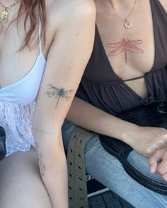 two women sitting next to each other with dragon tattoos on their chests and arms