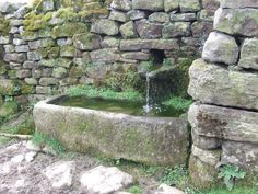 an old stone well with water coming out of it