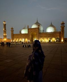 a person standing in front of a large building with many lights on it's sides