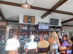 people sitting at tables in a bar watching tv