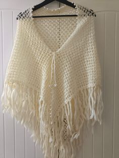 a white crocheted shawl hanging on a wall