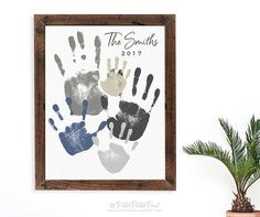 a wooden frame with handprints on it next to a potted plant