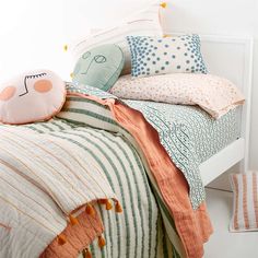 a white bed topped with lots of pillows next to a night stand and rugs