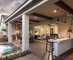 an outdoor kitchen and living room with a pool in the center is shown at dusk