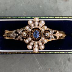 This magnificent bracelet bangle dates back to the Georgian era. It is crafted in 14K gold. Centered with a rich blue Ceylon sapphire, and accented with antique natural pearls, and diamonds. Bracelet Circumference: 21.0 mm Approximate Carat Weight of Sapphire: 0.60 Carats Approximate Carat weight of Diamond: 0.85 carats Smallest Measurement of Pearl: 1.5 mm x 1.5 mm Largest Measurement of Pearl: 4.0 mm x 4.0 mm Weight: 23.7 grams Metal Purity: 14KT Gold Diamonds Bracelet, Georgian Era, Ceylon Sapphire, Sapphire Bracelet, Bracelet Bangle, Sapphire Diamond, Natural Pearls, 14kt Gold, Chain Link Bracelet