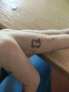 a person's hand with a small cat tattoo on the middle finger and an arrow in the middle