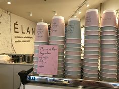 stacks of pink and grey cups sitting on top of a counter in a store with writing on them