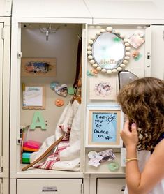 a woman is looking into a white cabinet