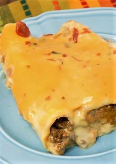 a blue plate topped with cheese and meat covered in gravy on top of a colorful table cloth