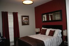 a bedroom with red walls and white bedding, two framed pictures on the wall