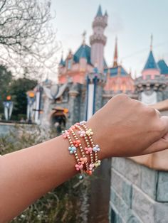 a woman's arm with several bracelets on it in front of a castle