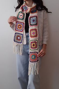 a woman is wearing a crocheted scarf with fringes on the sides and an embellishment in the middle