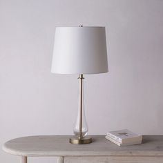 a white lamp sitting on top of a table next to a book