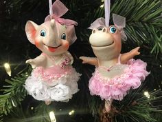 two ornaments hanging from a christmas tree decorated with pink and white tutu skirted elephants