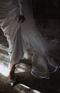 a woman in white dress walking across a floor