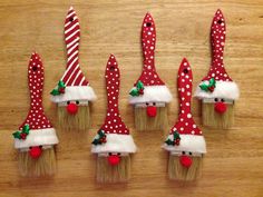 six toothbrushes with santa hats and bows on them sitting on a wooden surface