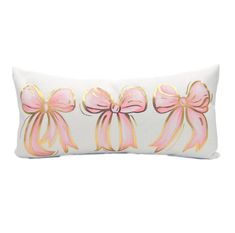 a white pillow with pink bows and gold foil on the front, sitting on a white surface