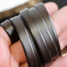 a person is holding some brown leather bracelets